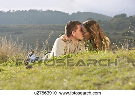 Young couple lying and kissing in field View Large Photo Image Stock Image - Young couple lying and kissing in field. Fotosearch