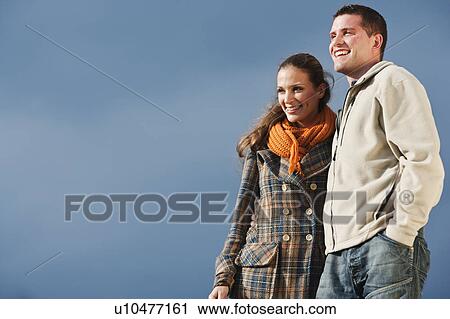 Stock Image - Young couple smiling while hugging. Fotosearch