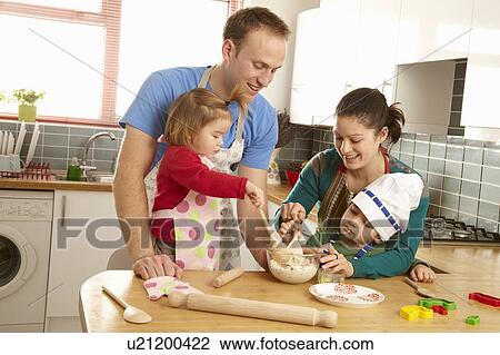 Stock Image - Young family cooking together in kitchen. Fotosearch