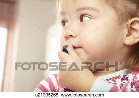 Young girl eating a blueberry View Large Photo Image Stock Photography - Young girl eating a blueberry. Fotosearch
