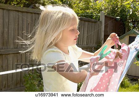 Stock Image - young girl hanging out clothes. Fotosearch