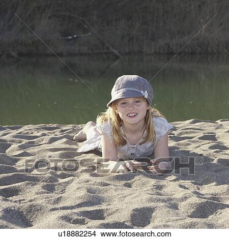 Young girl laying on sand by river View Large Photo Image Picture - Young girl laying on sand by river. Fotosearch