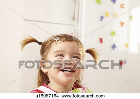 Picture - Young girl smiling in kitchen. Fotosearch