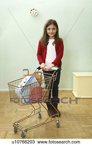 Stock Image - young girl with shopping trolly. Fotosearch