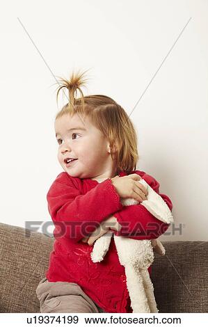 Stock Photo - Young girl with teddy bear on sofa. Fotosearch