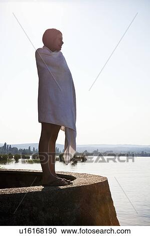 Stock Image - Young girl wrapped in towel by lake. Fotosearch