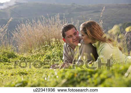 Young loving couple lying in field View Large Photo Image Stock Photograph - Young loving couple lying in field. Fotosearch