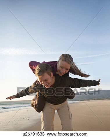 Stock Image - Young man giving woman piggyback ride. Fotosearch
