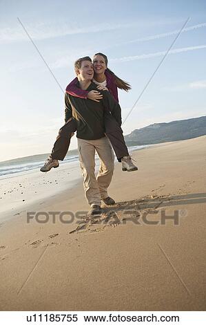 Stock Photography - Young man giving woman piggyback ride. Fotosearch