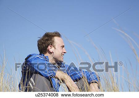 Stock Photo - Young man sitting relaxing in long grass. Fotosearch