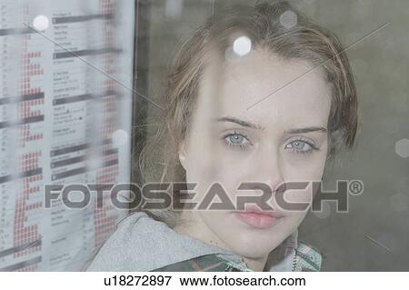 Stock Photo - Young woman at bus shelter in rain. Fotosearch