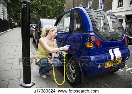 Young woman charging electric car View Large Photo Image Picture - Young woman charging electric car. Fotosearch