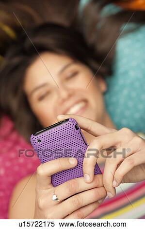 Young woman checking her phone, smiling View Large Photo Image Stock Photography - Young woman checking her phone, smiling. Fotosearch