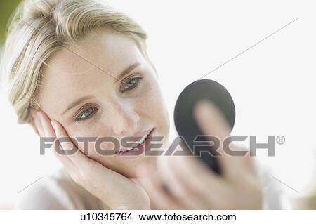Picture - Young woman checking make-up. Fotosearch