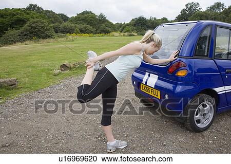 Young woman exercising by electric car View Large Photo Image Stock Image - Young woman exercising by electric car. Fotosearch
