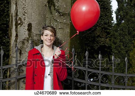 Stock Photo - Young woman holding a red baloon. Fotosearch
