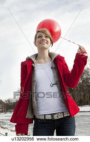 Stock Photograph - Young woman holding red ballon. Fotosearch