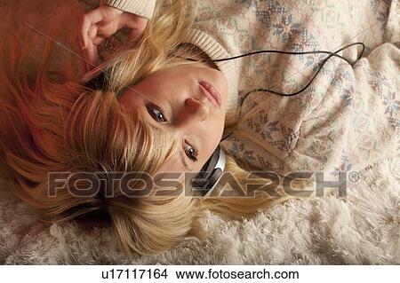 Young woman lying down with headset View Large Photo Image Picture - Young woman lying down with headset. Fotosearch