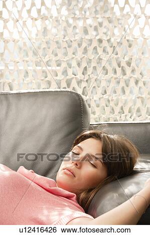 Young woman relaxing on a sofa View Large Photo Image Stock Photograph - Young woman relaxing on a sofa. Fotosearch