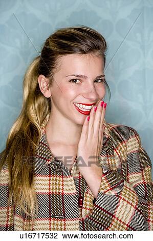 Young woman smiles with hand to mouth View Large Photo Image Stock Image - Young woman smiles with hand to mouth. Fotosearch