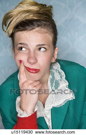 Young woman thinks finger to cheek View Large Photo Image Stock Image - Young woman thinks finger to cheek. Fotosearch