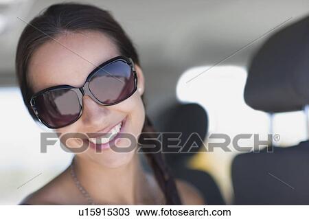 Stock Image - Young woman wearing big sunglasses. Fotosearch