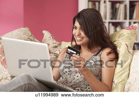 Stock Photo - Young woman with credit card at laptop. Fotosearch