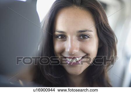 Picture - Young woman with dark hair in car smiling. Fotosearch