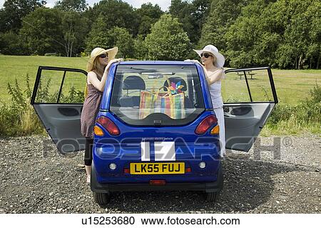 Young women standing by electric car View Large Photo Image Stock Image - Young women standing by electric car. Fotosearch