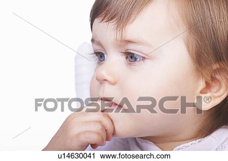 Stock Image - Baby girl chewing her finger. Fotosearch
