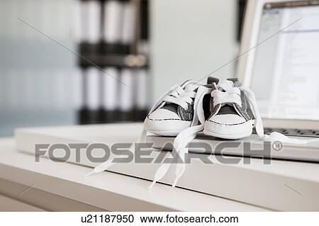 Stock Image - Baby shoes on laptop. Fotosearch