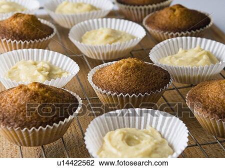 Stock Image - Baked cupcakes and batter on rack. Fotosearch