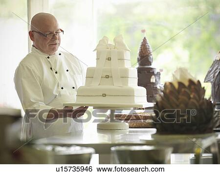 Baker checking decorative wedding cake View Large Photo Image Stock Photograph - Baker checking decorative wedding cake. Fotosearch
