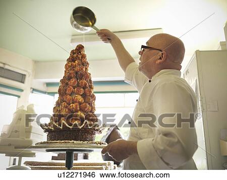 Stock Photograph - Baker pouring sugar over decorated cake. Fotosearch
