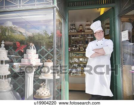Baker standing in cake shop View Large Photo Image Stock Image - Baker standing in cake shop. Fotosearch