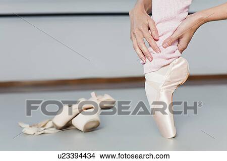 Picture - Ballet dancer examining toes on pointe. Fotosearch