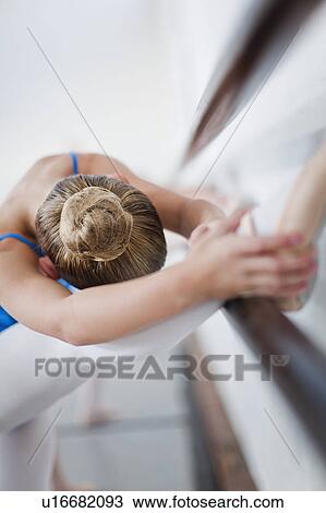Stock Image - Ballet dancer stretching at barre. Fotosearch