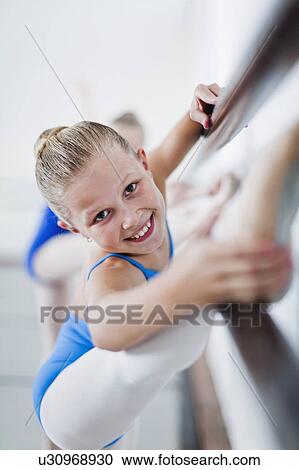 Stock Image - Ballet dancer stretching at barre. Fotosearch