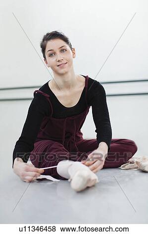 Stock Photo - Ballet dancer tying her shoe in studio. Fotosearch