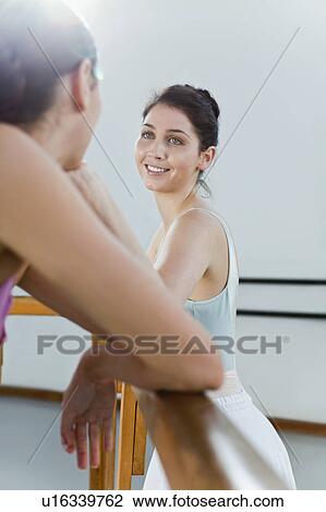 Stock Image - Ballet dancers talking at barre. Fotosearch
