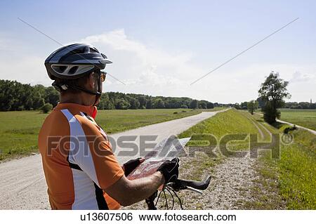 Biker reading map on rural road View Large Photo Image Stock Photograph - Biker reading map on rural road. Fotosearch