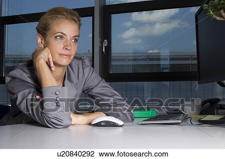 Bored businesswoman sitting at desk View Large Photo Image Stock Image - Bored businesswoman sitting at desk. Fotosearch