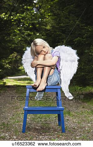 Bored girl in wings sitting on stool View Large Photo Image Stock Image - Bored girl in wings sitting on stool. Fotosearch