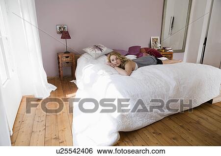 Stock Photograph - Bored woman laying on bed. Fotosearch