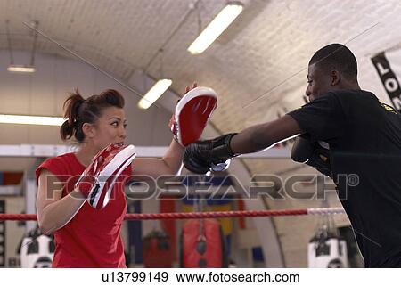 Stock Photo - Boxer training with coach in gym. Fotosearch