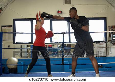Stock Image - Boxer training with coach in ring. Fotosearch