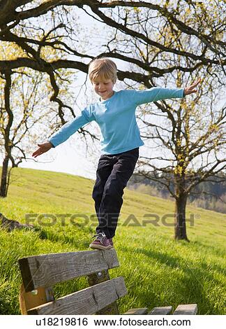 Stock Photograph - Boy balancing along park bench. Fotosearch