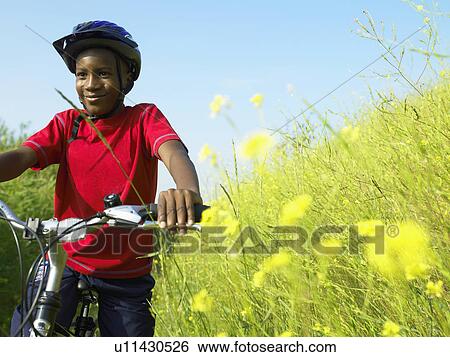 Boy biking in field of flowers View Large Photo Image Stock Photograph - Boy biking in field of flowers. Fotosearch