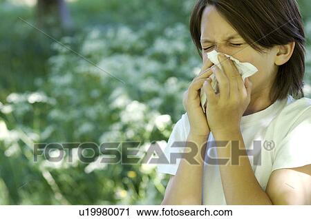 Stock Image - Boy blowing his nose in field of flowers. Fotosearch