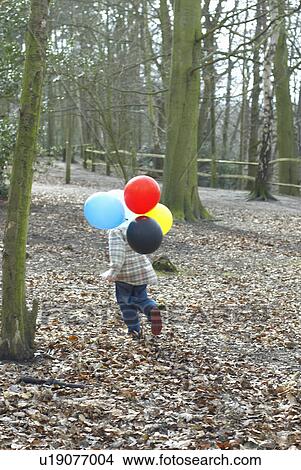 Boy carrying bunch of balloons outdoors View Large Photo Image Picture - Boy carrying bunch of balloons outdoors. Fotosearch